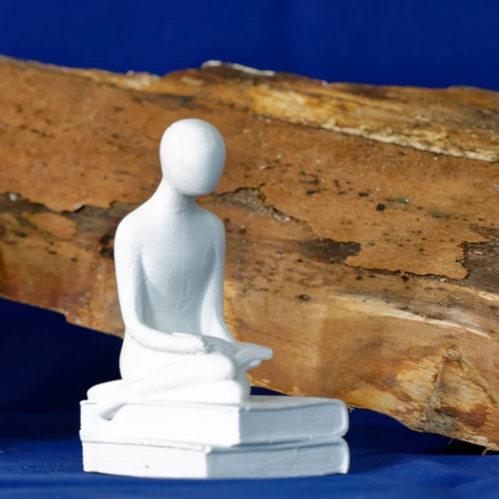 Handgegossene Deko aus Gips - Figur sitzt, die Beine untergeschlagen, auf einem Stapel Bücher und liest - Geschenkideen aus Gips, Wohnideen aus Gips
